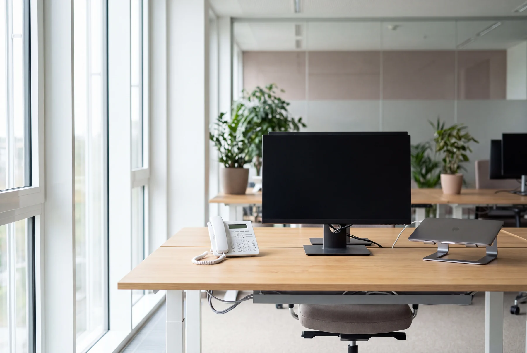 Fertig eingerichteter Arbeitsplatz am Fenster mit Monitor, Tischtelefon und Laptop, Kabel sauber verlegt